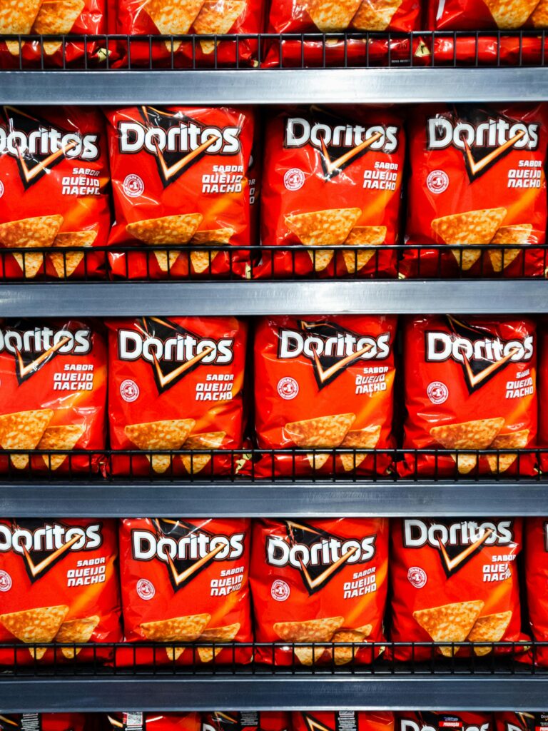 Neatly arranged Doritos pouches on a store shelf in Brazil, showcasing bright packaging.